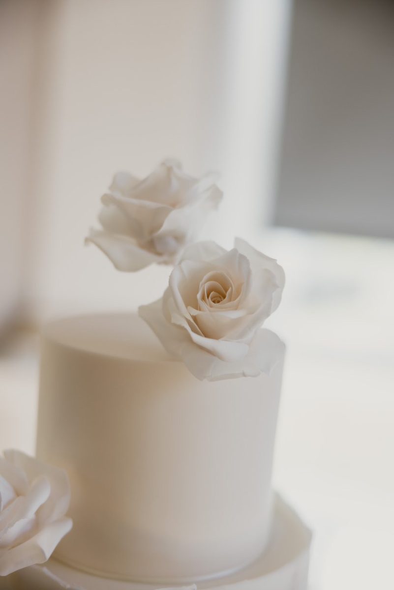 Wedding cake in South Shields. A white two-tiered cake with three white rose decorations.