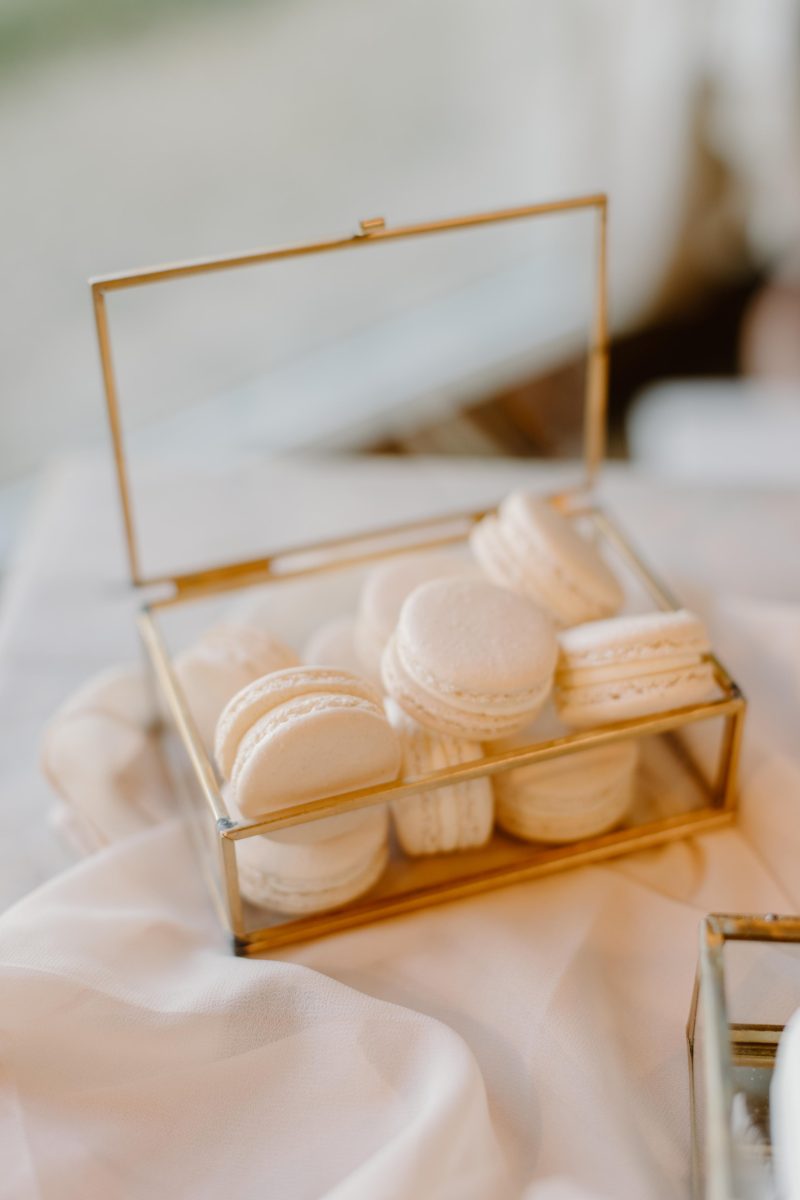A glass box filled with a variety of white macarons, placed on a soft white fabric.