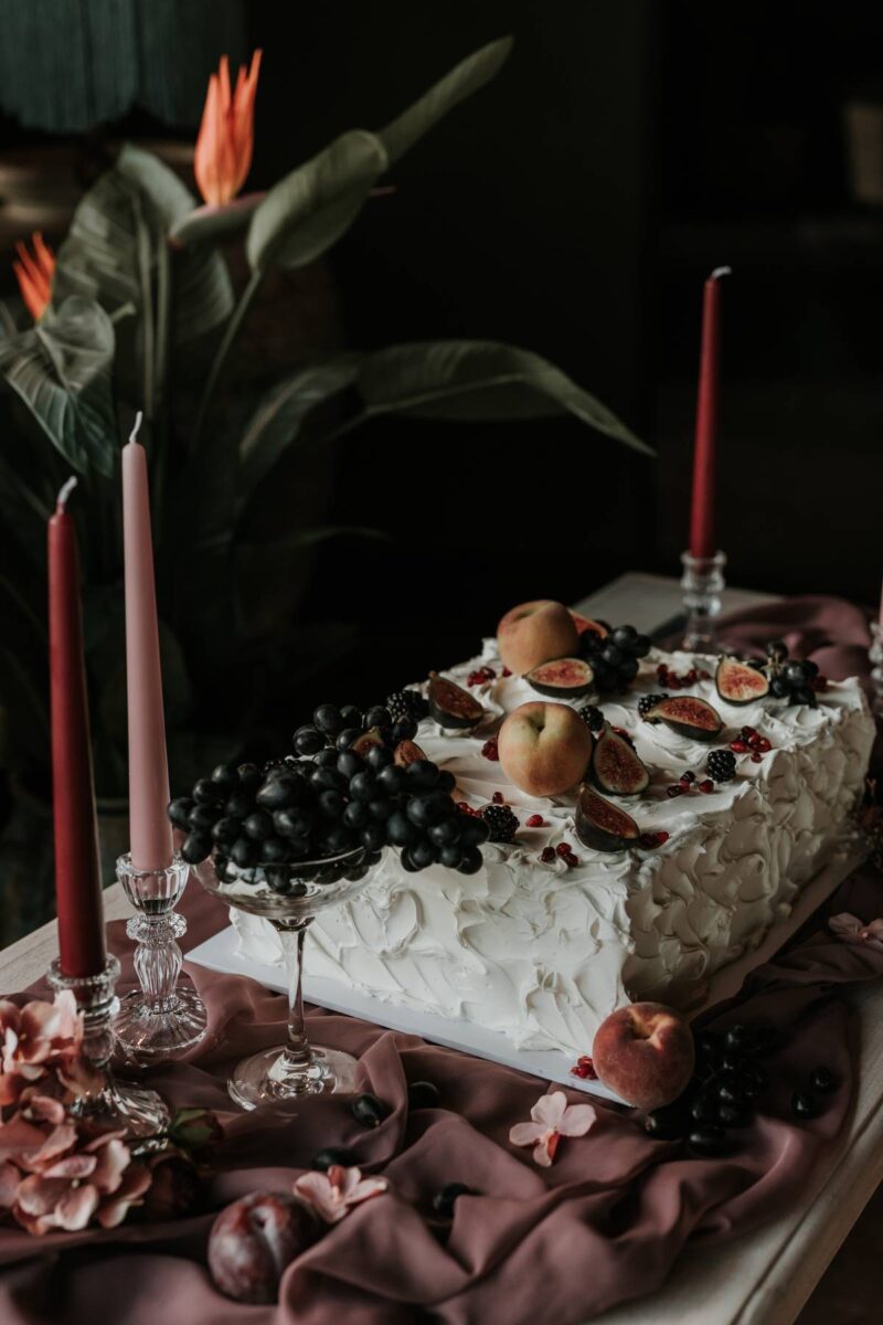 A rectangle wedding cake topped with fresh fruit in a rustic style